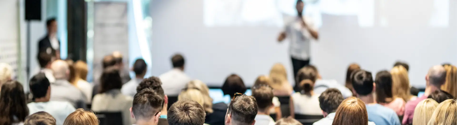 Wide conference audience attending a leadership session with speaker on stage