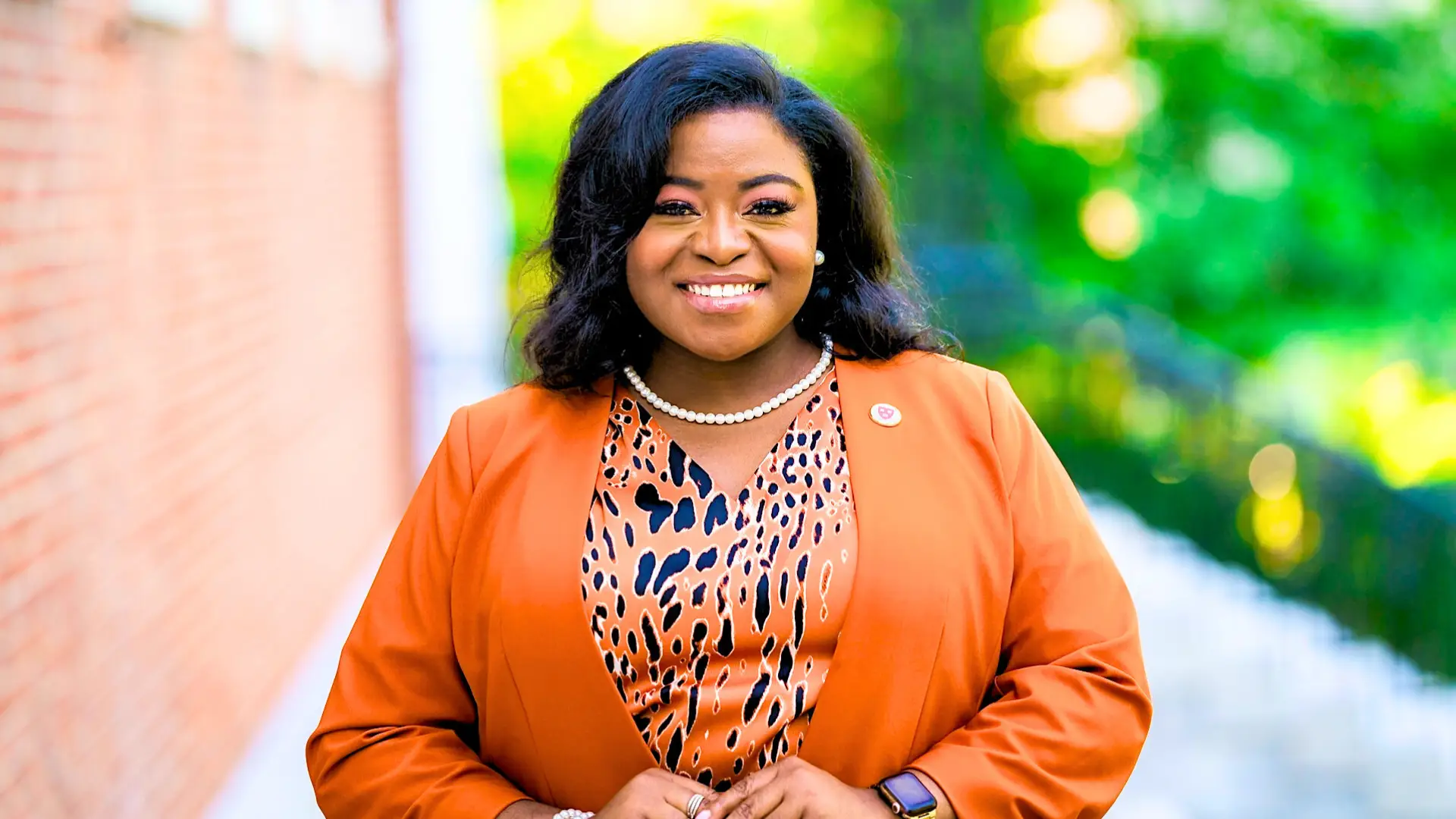 Program Director Chassity Keandra Coston professional portrait in orange blazer with pearl necklace